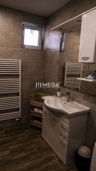 Bathroom with a sink, cabinet, ladder radiator, and floor with wooden decor.