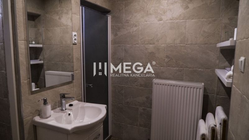 A bathroom with a shower, sink, and radiator, ideal for hotels and guesthouses.