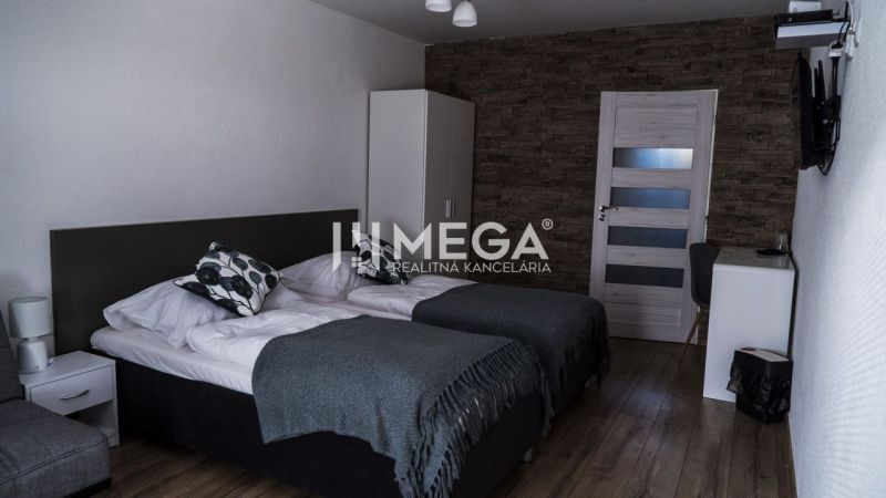 Interior of a room with two beds, a wall with stone decor, flooring with wooden decor.