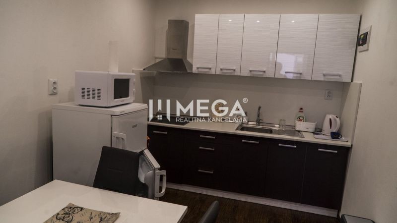 A kitchen with a microwave, refrigerator, and sink, wood-patterned flooring in hotel premises.