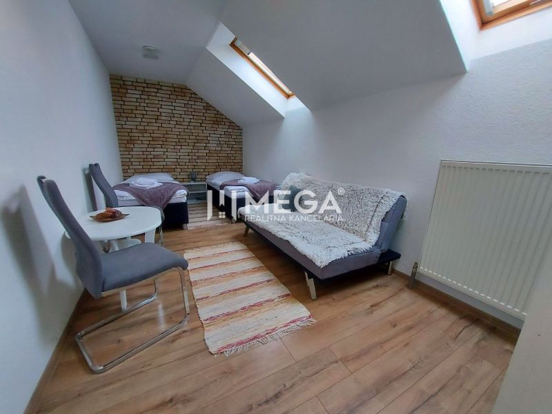 Attic room with two beds, a sofa, and a wooden decor floor in hotels and guesthouses.