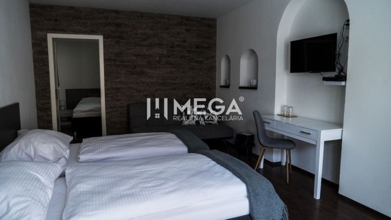A hotel room with a tiled wall, a floor with a wooden decor, and a writing desk.