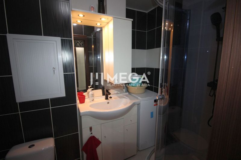 Bathroom in a holiday apartment with a shower, sink, and washing machine.