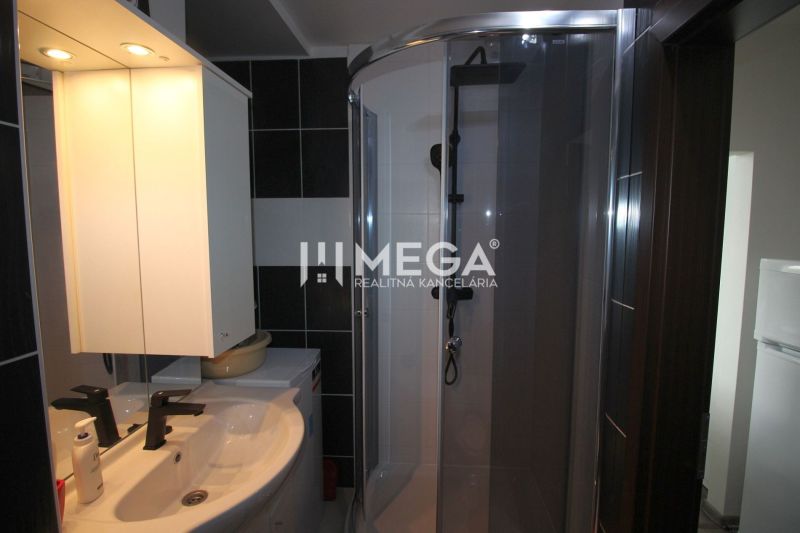 Bathroom in a holiday apartment with a sink, shower, and mirror with lighting.
