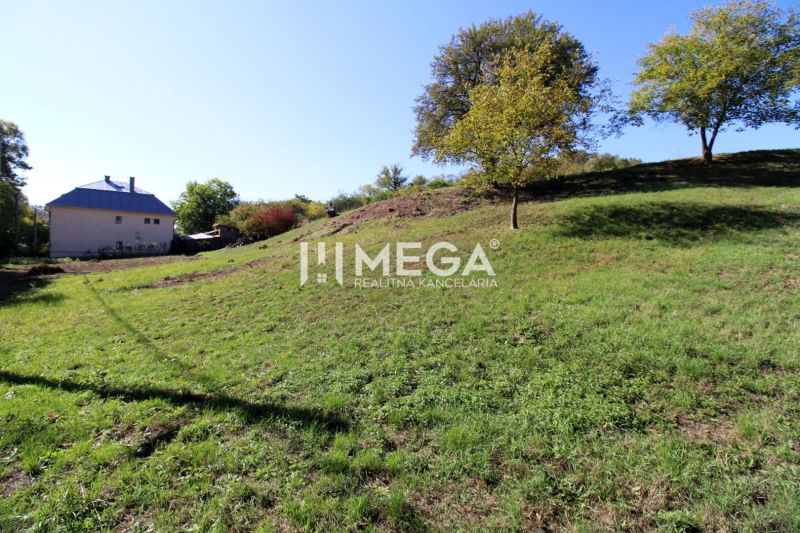 Green sloping residential land in Vyšné Ladičkovce with a view of the house and trees.