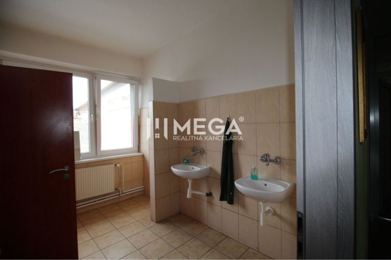 Bathroom in offices with two sinks and a window, butter-cream tiles.