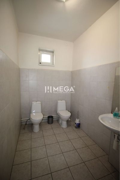 Office restroom with two toilets and a sink, tiled with white tiles.