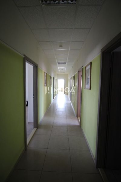 A hallway in offices with pale walls and light tiled flooring.