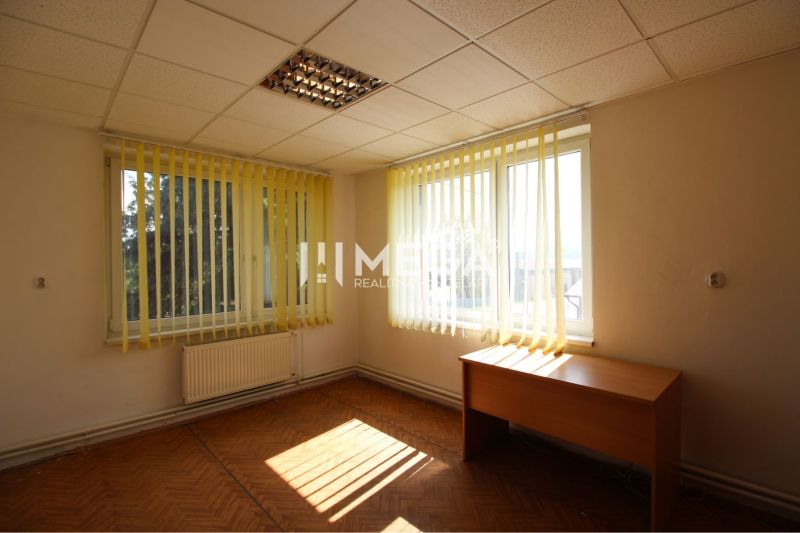 Bright office with vertical blinds and wood-patterned flooring.