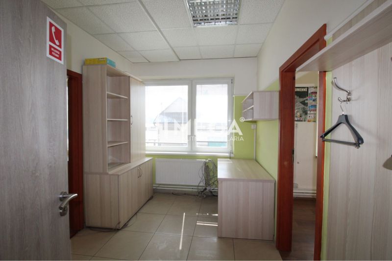 An office interior with modern furniture and a window, offering a bright workspace.