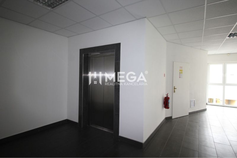 Offices with an elevator, light flooring, and a fire extinguisher in the hallway.