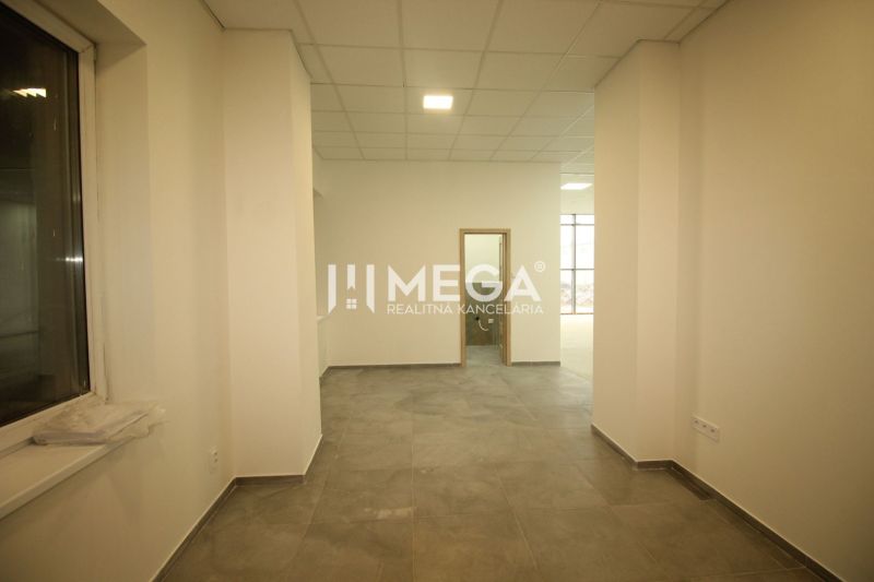 Commercial space with tiles, white walls, and a window, appears spacious and bright.