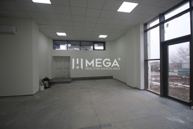 Commercial space with concrete flooring, large windows, and white walls.
