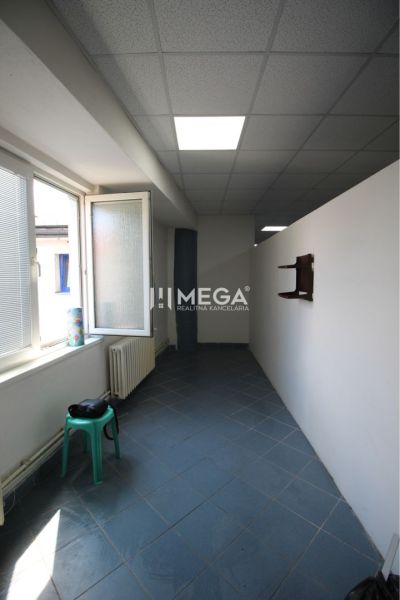 A narrow room with blue tiles and a large window in commercial premises.