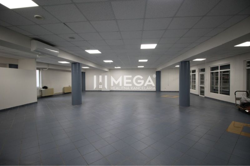 Spacious commercial premises with dark tiles and a suspended ceiling, suitable for business.