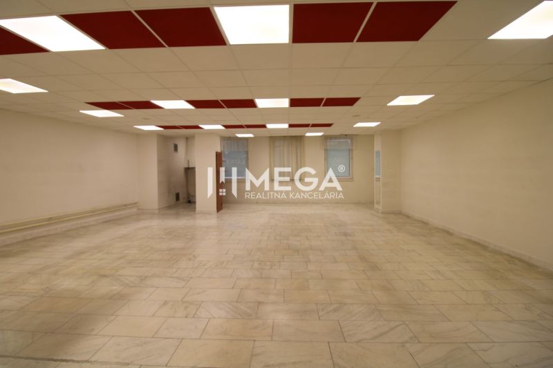 Spacious commercial spaces with tiled floors and a bright ceiling with red panels.