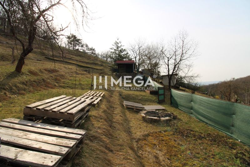 Gardens in Humenné at ZO Poniklec, a grassy slope with pallets and a wooden gazebo.