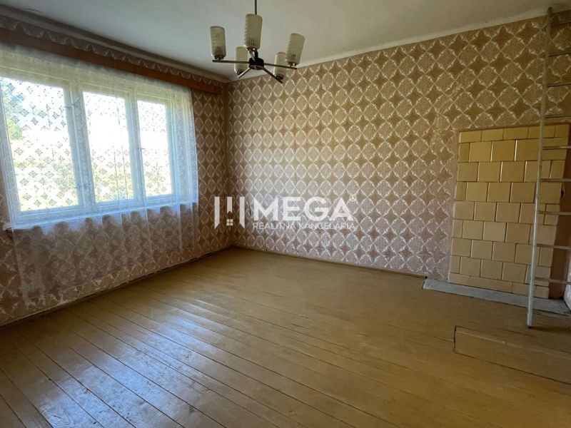 A family house with a wooden decor floor, patterned wallpaper, and a large window.