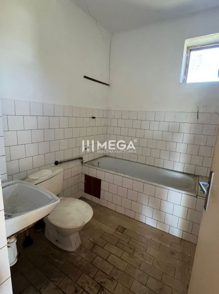 Bathroom with shower and toilet in a family house, basic interior with white tiles.