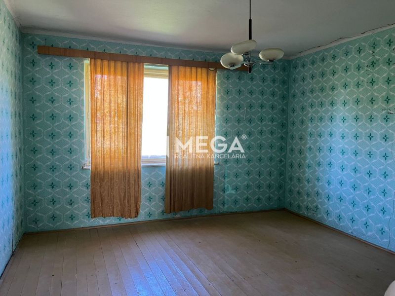 A room in a family house with patterned wallpaper and a wooden decor floor.
