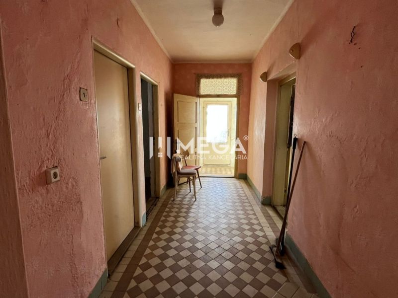 The interior of a family house with tiles, pink walls, and old furniture.