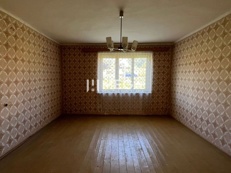 A room with wallpaper and wooden decor flooring in a family house.