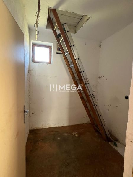 A ladder leads to the attic in a family house with a wooden decor floor.