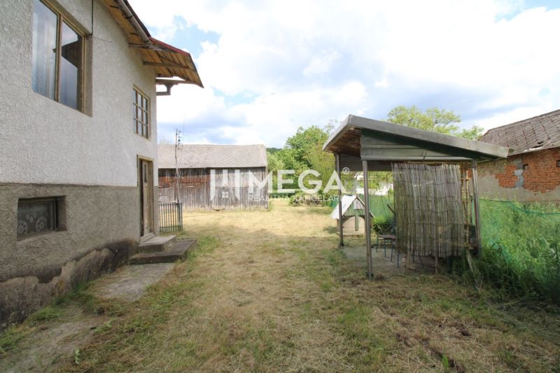 A garden by a family house in the village of Zbudská Belá, with a shelter and a wooden structure.