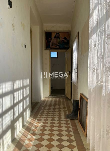A hallway in a family house with colorful tiles and a curtain, a painting hangs on the wall.