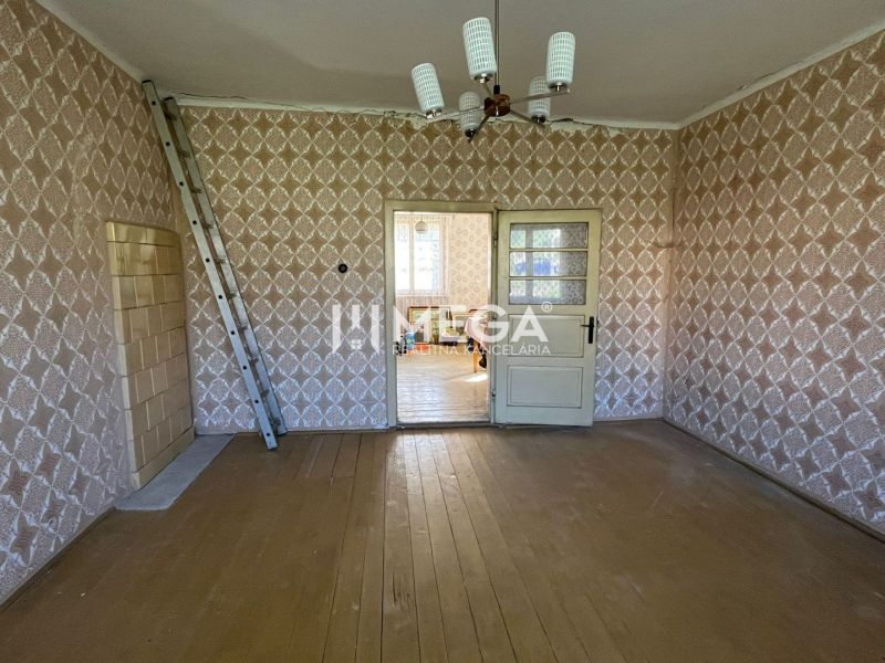 A room in a family house with a wooden decor floor and patterned wallpaper.