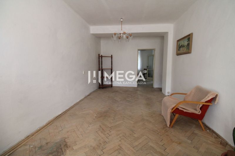 Living room with an old armchair and a floor with a wooden decor in a 2-room apartment.