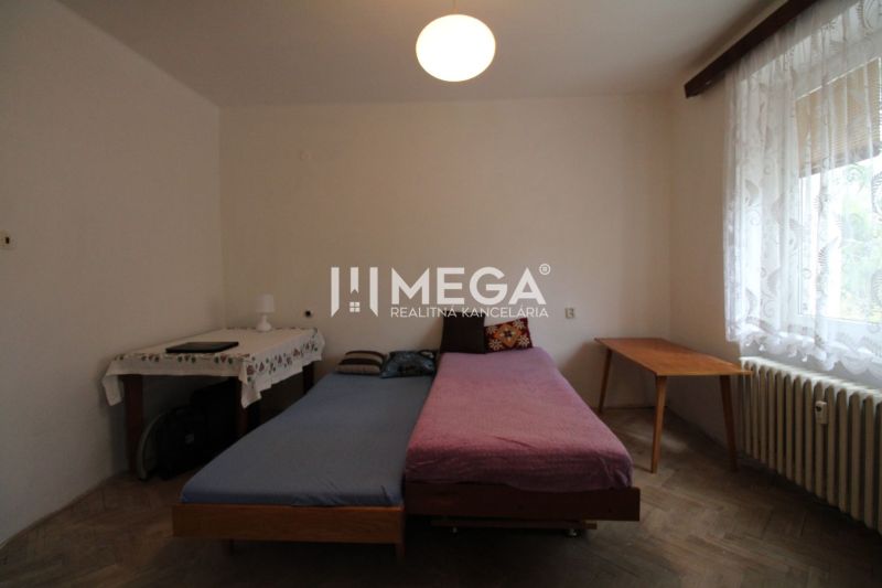 Bedroom in a 2-room apartment with a bed, a table, and a floor with a wooden decor.