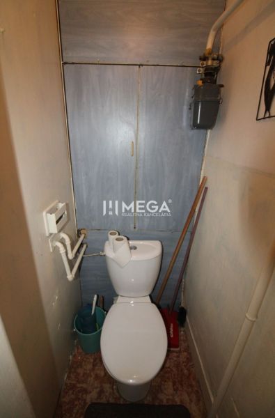 A toilet with a wooden decor in a 2-room apartment with basic amenities.