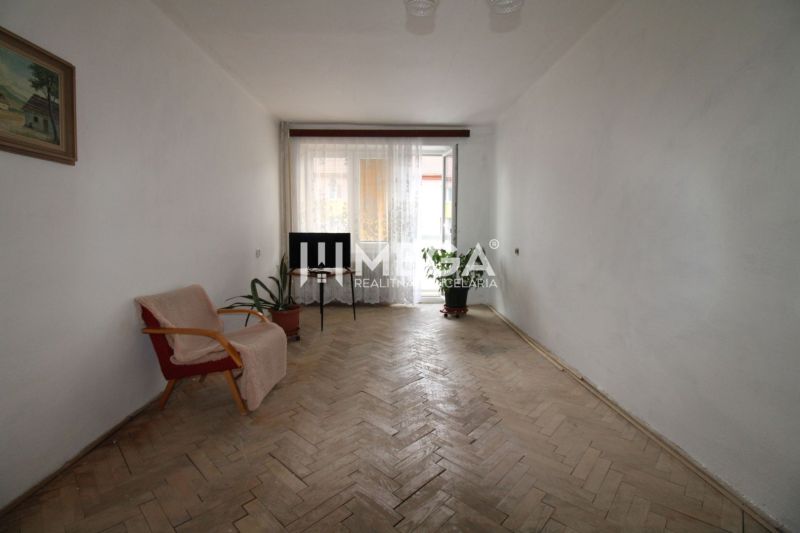 Living room in a two-room apartment with a wooden decor floor and simple furnishings.