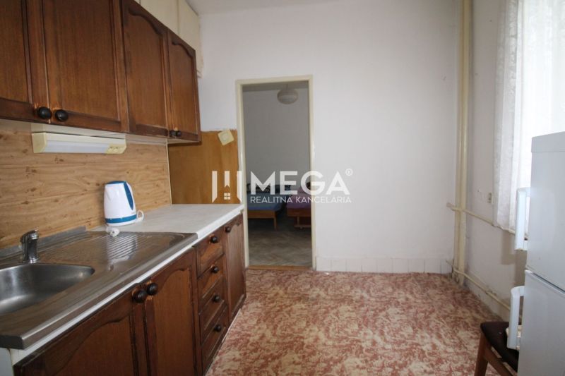 A kitchen in a 2-room apartment with wooden cabinets and a kettle on the counter.