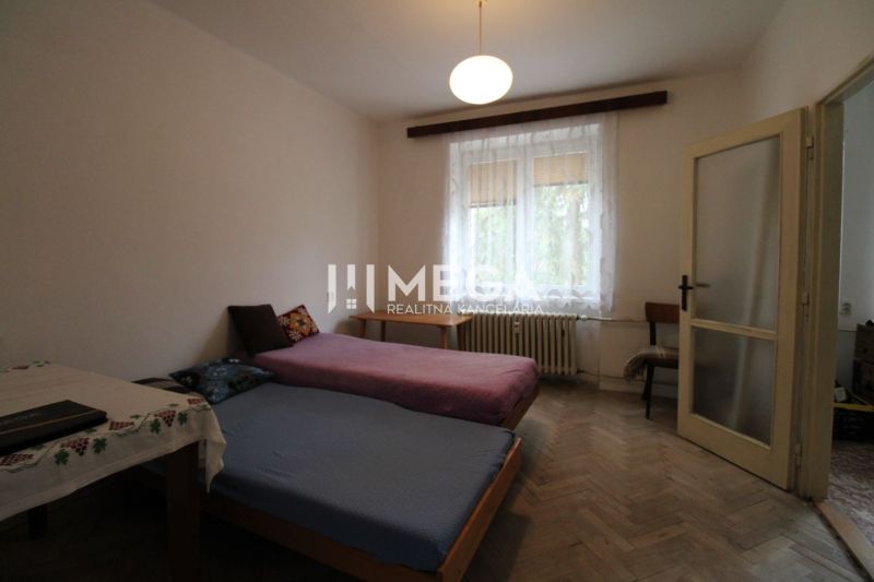 A bedroom with light furniture and beds in a two-room apartment with a wooden decor floor.