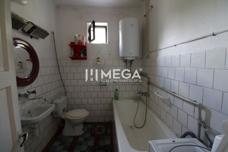 A bathroom in a family house with a bathtub, a sink, and a boiler on the wall.