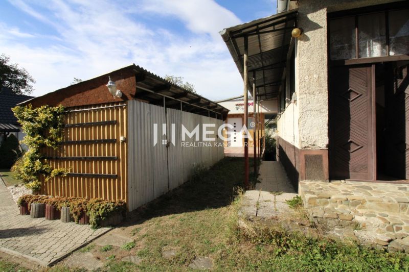 A family house in Volica with a metal shelter in the yard and climbing vegetation.