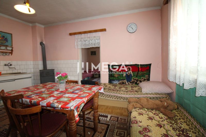Interior of a family house with a kitchen table, stove, and bed, floor with wooden decor.