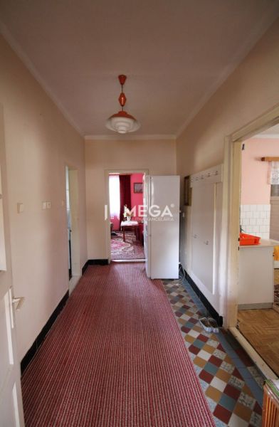 A hallway in a family house with carpet flooring and a retro light fixture.