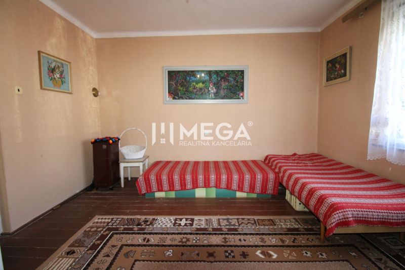 A room in a family house with carpets, beds, and a standing stove.