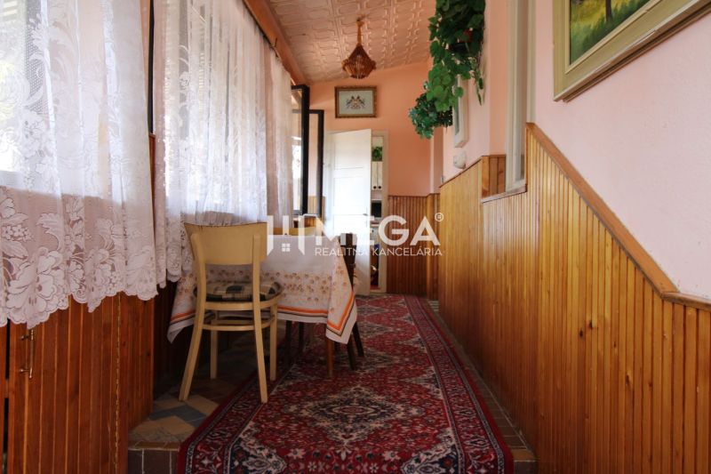 A hallway with a carpet runner, a table, curtains, and wood paneling in a family house.