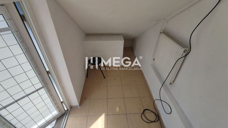 A narrow space with a radiator, a chair, and tiles in commercial premises.