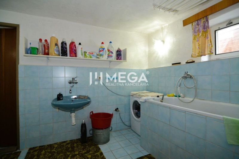 A bathroom in a family house with a bathtub, sink, and washing machine, with cleaning products on display.