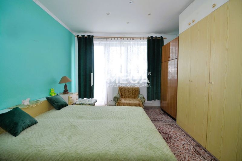 A bedroom in a family house with a turquoise wall, a large bed, and wardrobes.