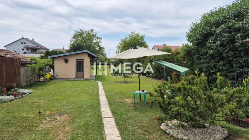 The garden of a family house in Lackovce with a lawn, seating area, and a small structure.