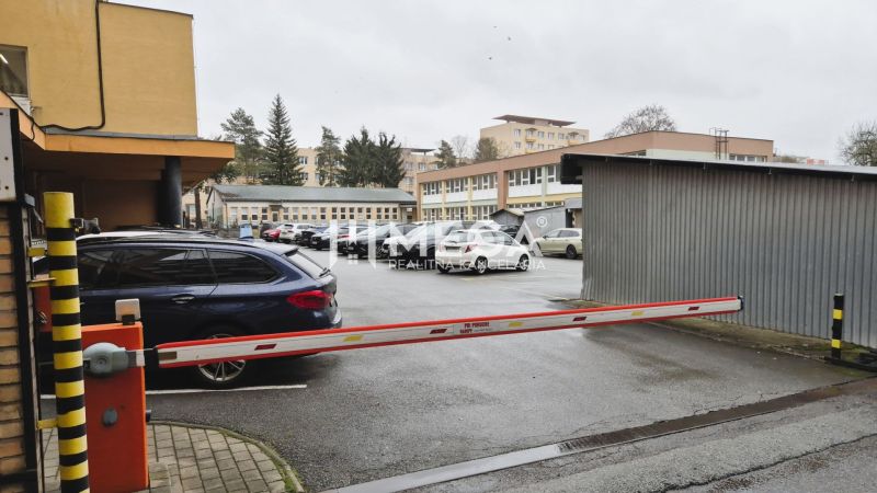 Parking lot in front of the offices on 26th November Street in Humenné with a barrier and cars.