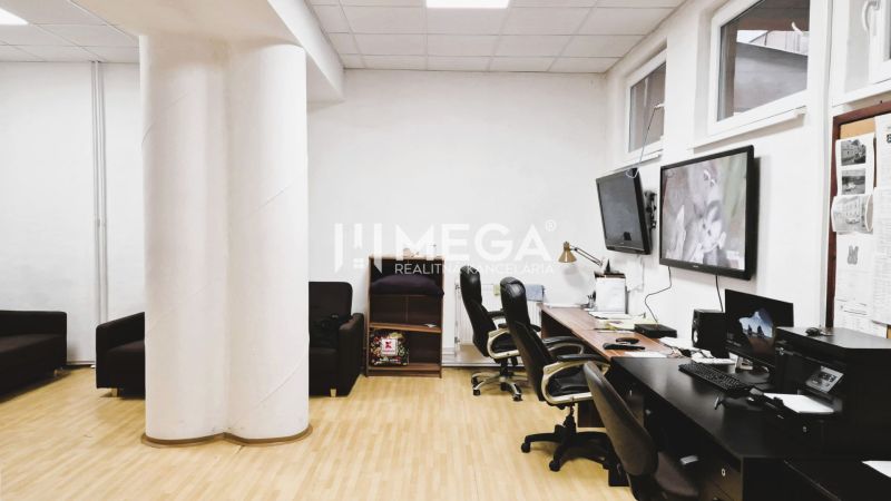 An office with a wooden decor floor, desks, chairs, and screens on the wall.