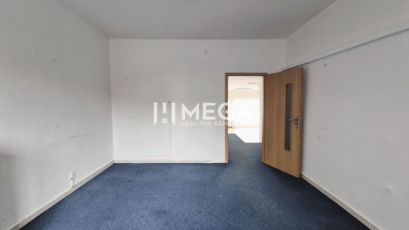 Commercial space with blue carpet and light wall, closed wooden door.