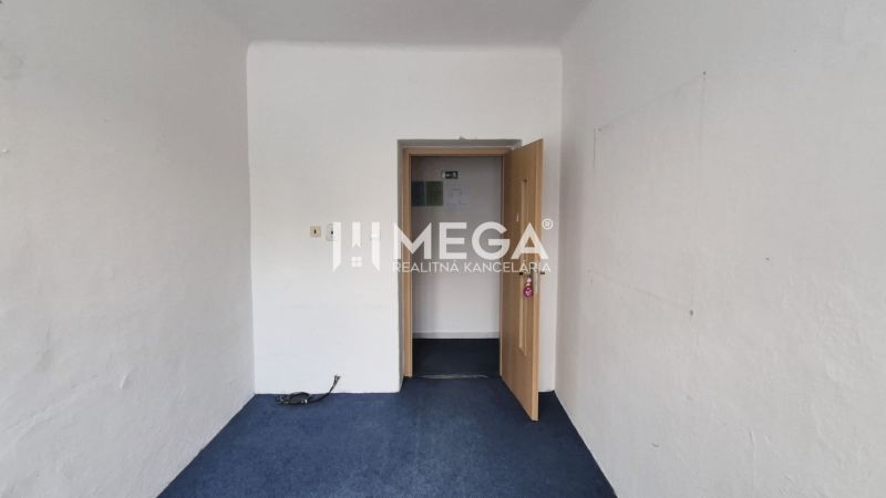 A white room with a blue carpet and open doors in a commercial space.